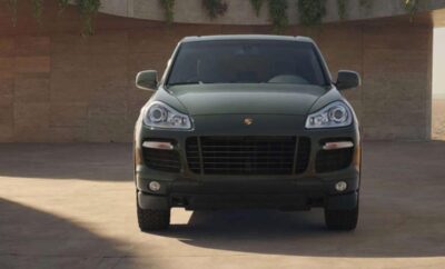 A black Porsche SUV parked on a driveway in front of a house.