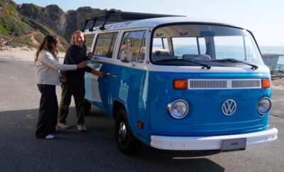 Person standing next to a blue vintage Volkswagen van.