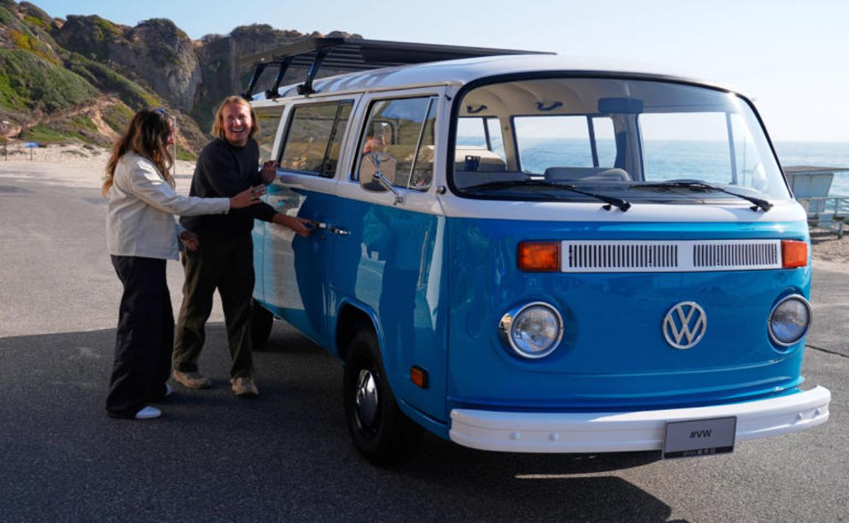 Person standing next to a blue vintage Volkswagen van.