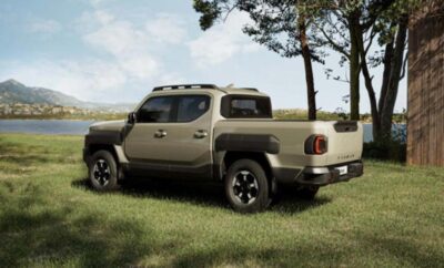 A rugged beige pickup truck parked on grass near trees under a blue sky.