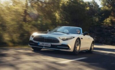 A sleek white convertible sports car driving on a sunlit road.