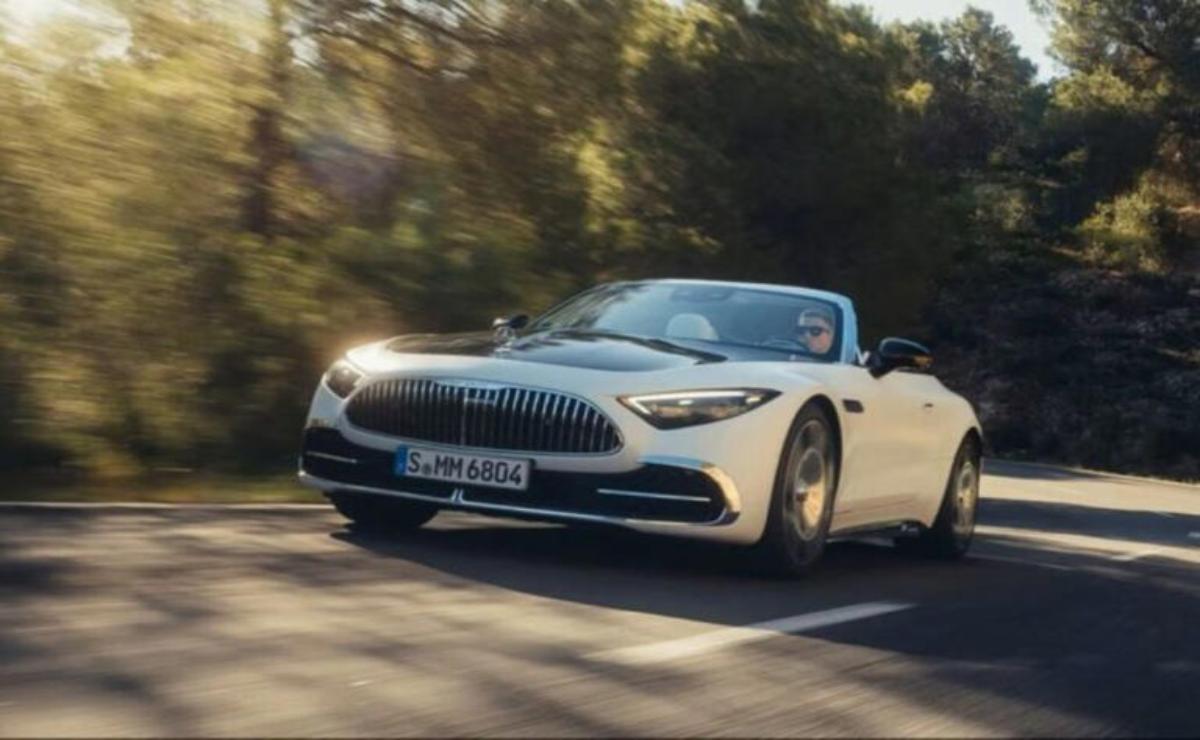 A sleek white convertible sports car driving on a sunlit road.