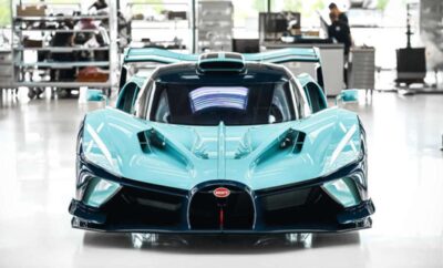 A sleek turquoise Bugatti supercar on display indoors.