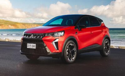 Red modern electric SUV parked on road under blue sky.