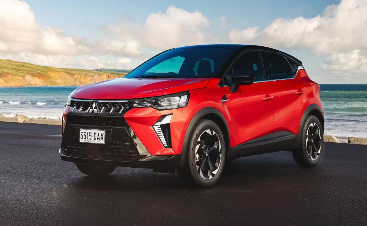 Red modern electric SUV parked on road under blue sky.