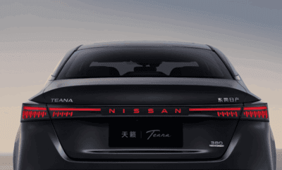 Rear view of a black Nissan Teana with illuminated tail lights.