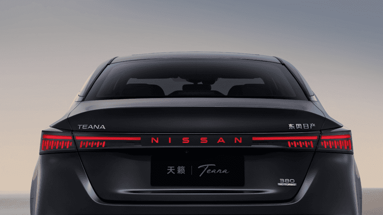 Rear view of a black Nissan Teana with illuminated tail lights.