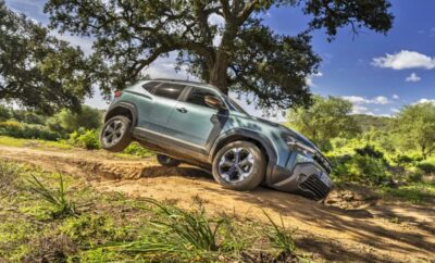 A rugged SUV climbing a steep dirt hill under a clear blue sky.