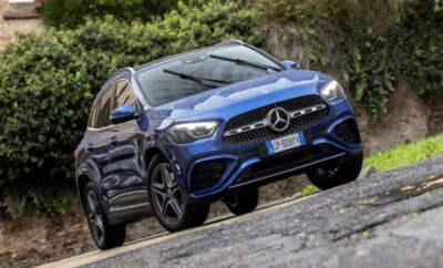 A blue Mercedes-Benz SUV parked on a rocky surface with greenery in the background.