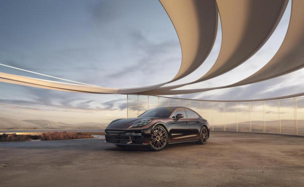 A sleek black sports car parked under a modern circular architectural structure at sunset.