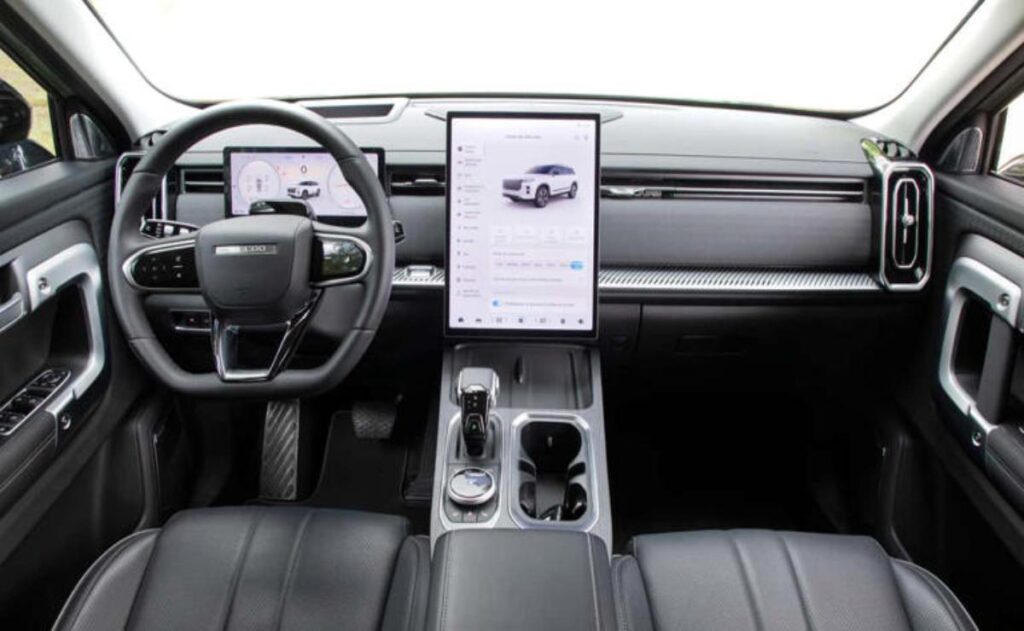 A man working on his laptop and writing in a notebook at a desk.