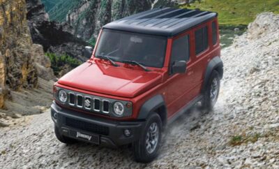 A red SUV driving on a rocky terrain near a river.
