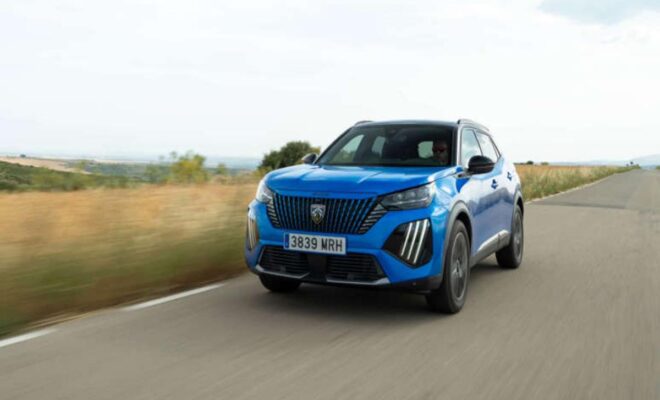 Blue Peugeot SUV driving on a road with scenic background.