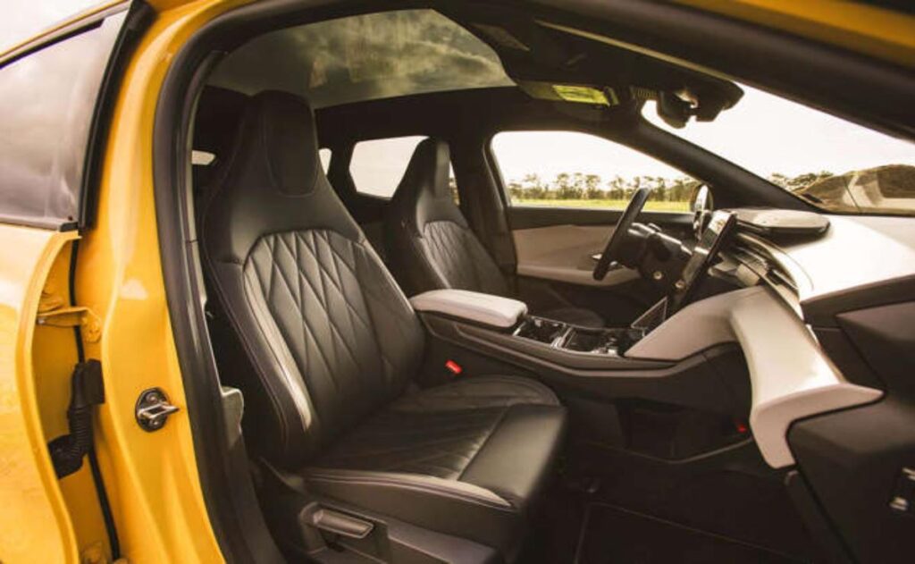 A man working on his laptop and writing in a notebook at a desk.