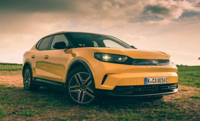 Yellow modern SUV parked on grassy terrain under a moody sky.