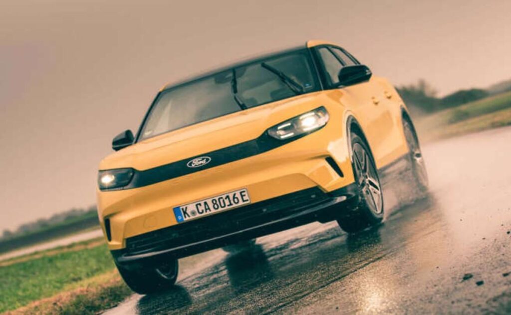 A man working on his laptop and writing in a notebook at a desk.