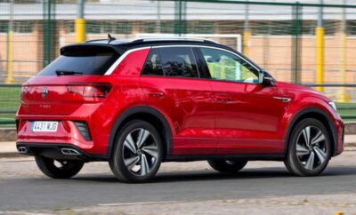 Red compact SUV driving on a city street.