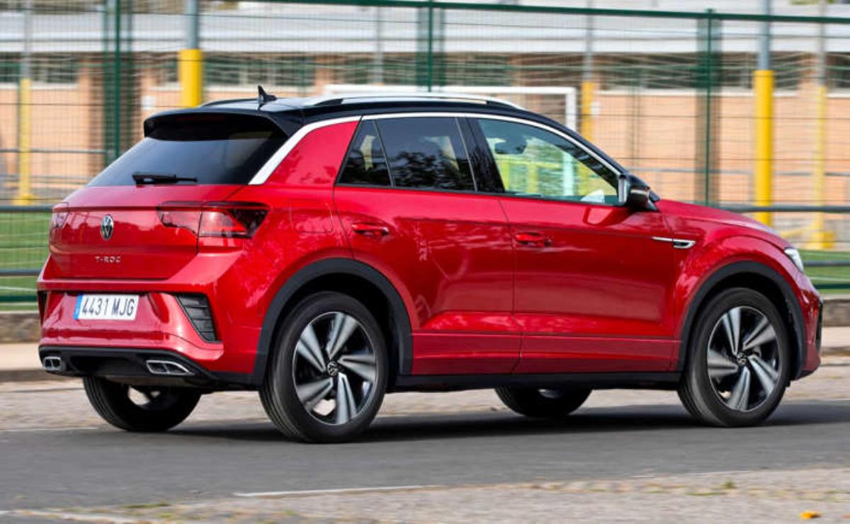 Red compact SUV driving on a city street.