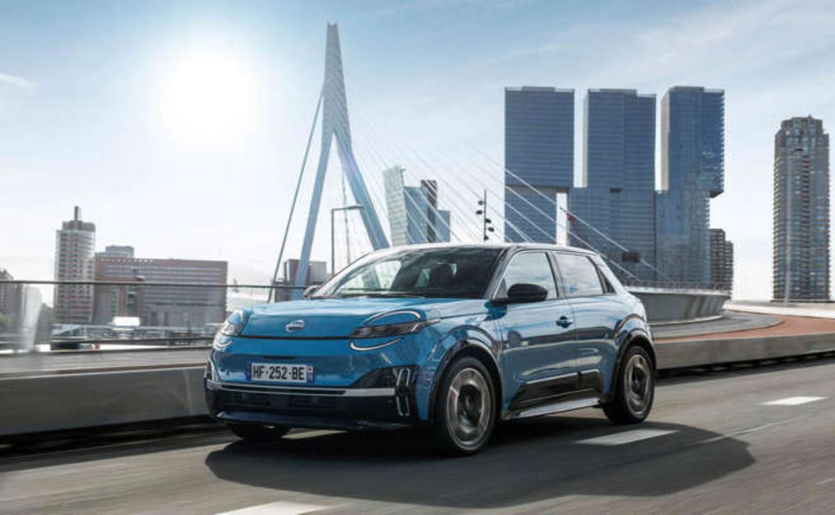 A blue electric car driving in a city with modern buildings in the background.