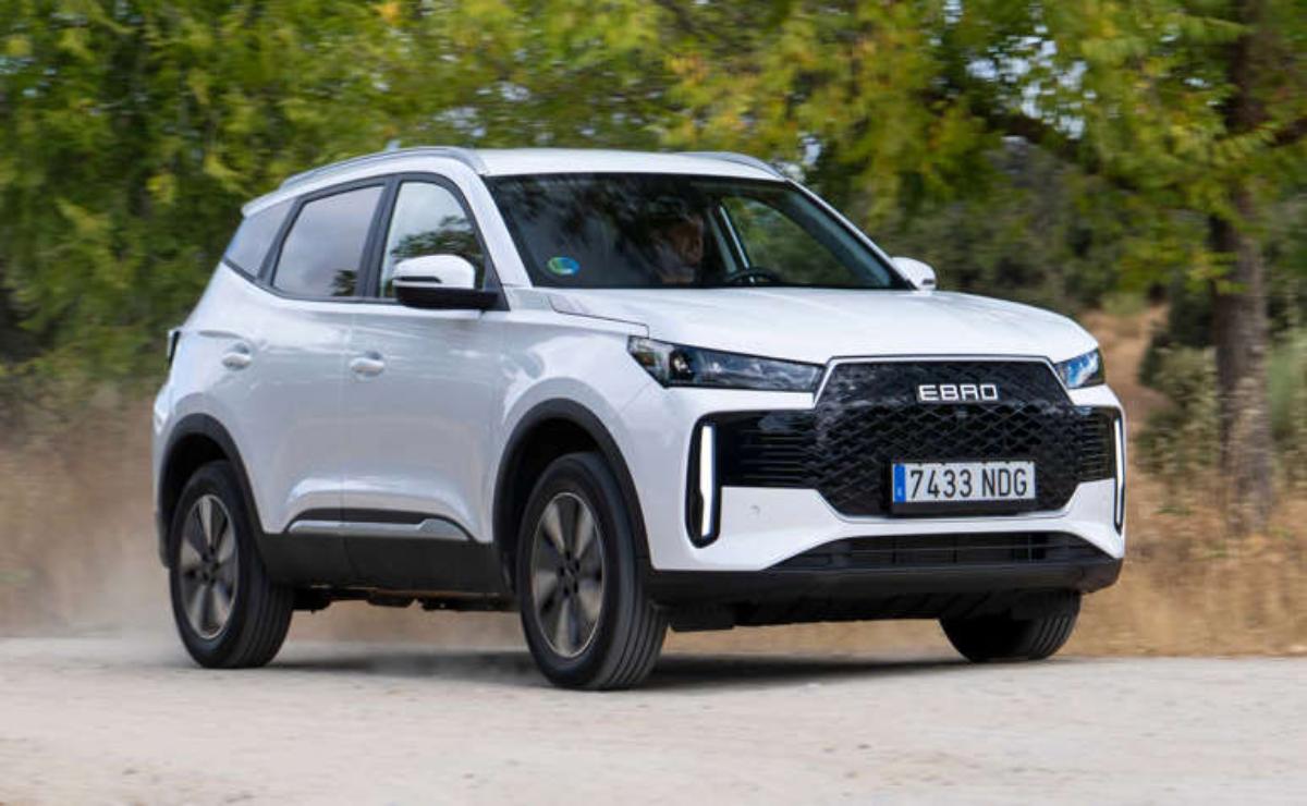 A white SUV driving on a road with greenery in the background.
