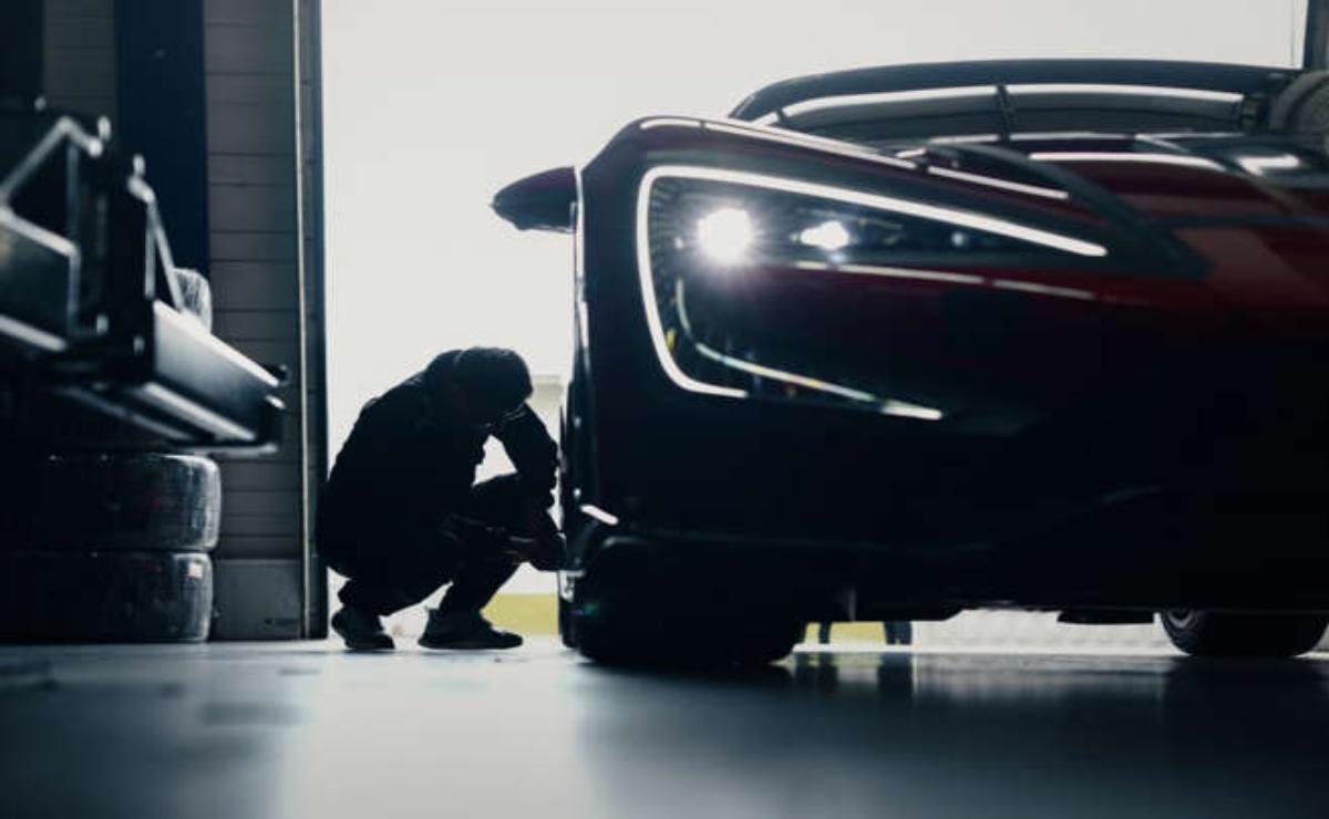 A person working on a sleek car in a garage.