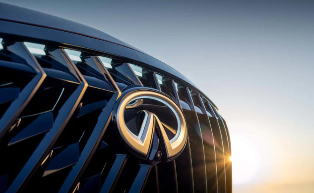 Close-up of Infiniti car grille with logo at sunset.