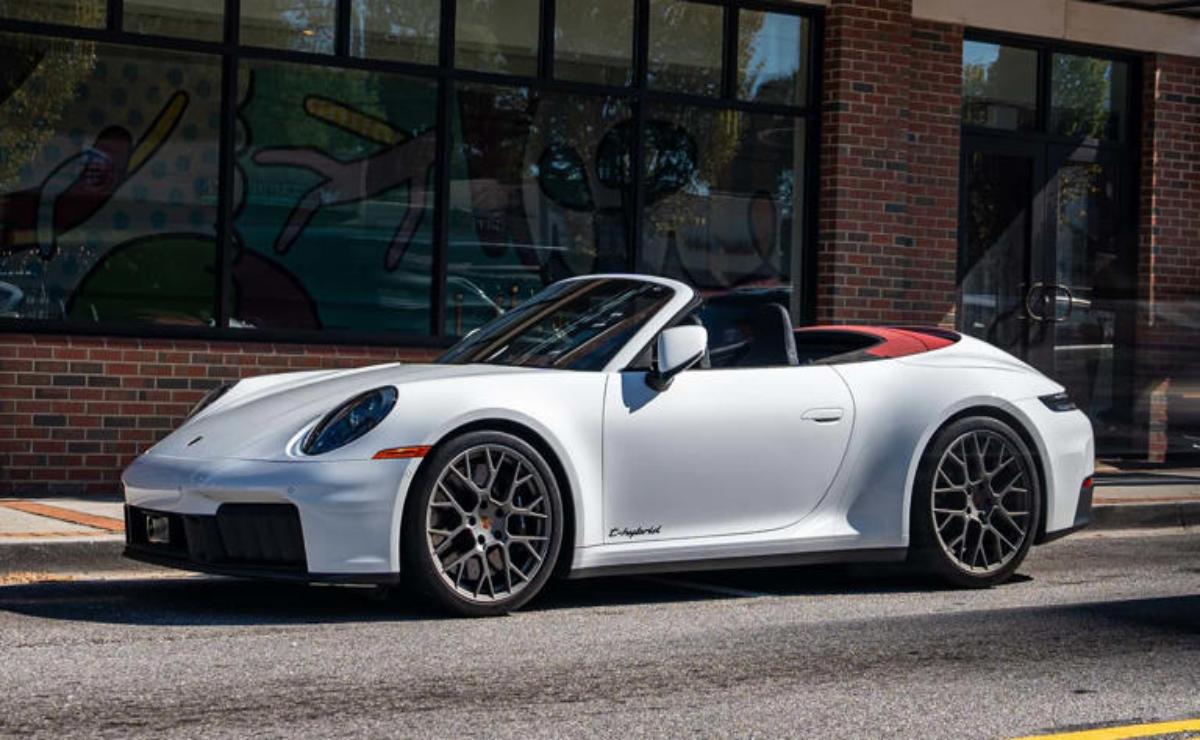 White Porsche convertible sports car parked near a brick building.