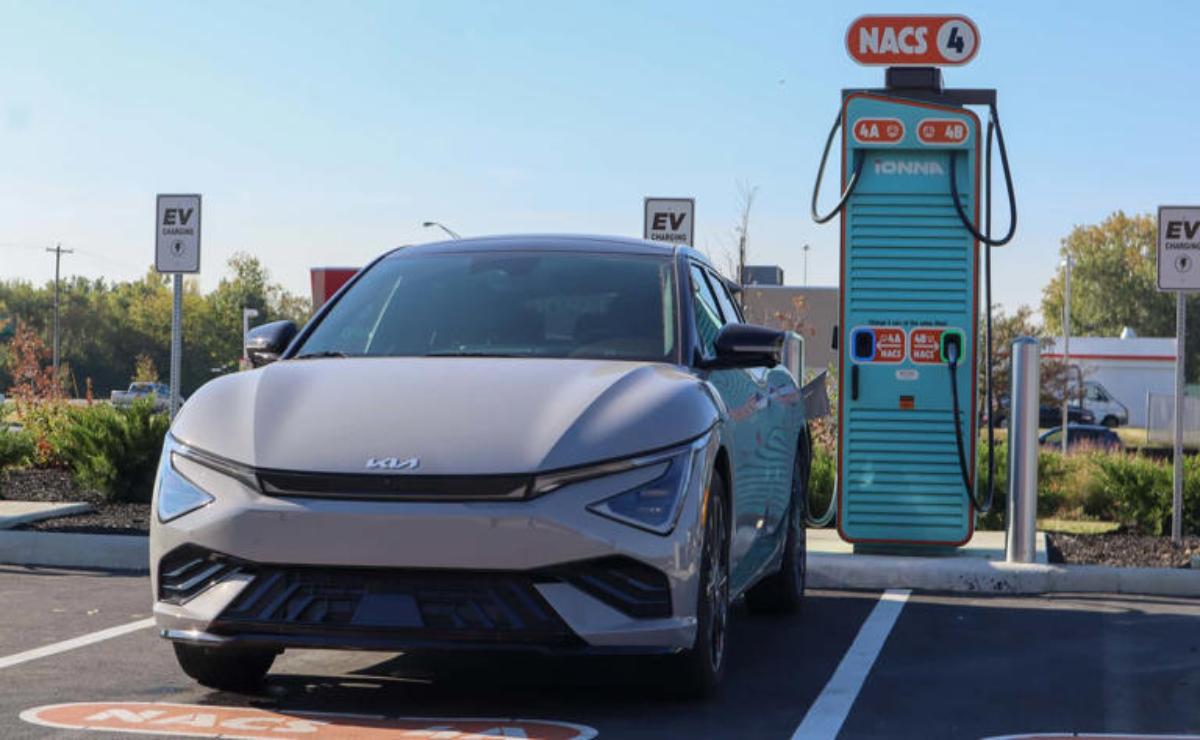 Electric car charging at a fast charger station on a sunny day.