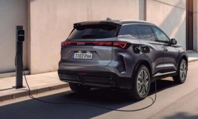 A sleek electric SUV charging at a station on a city street.