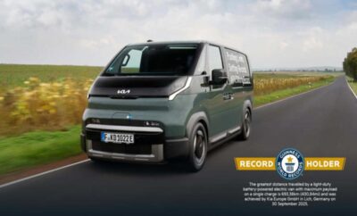 A sleek, modern electric van parked on a country road under a cloudy sky.