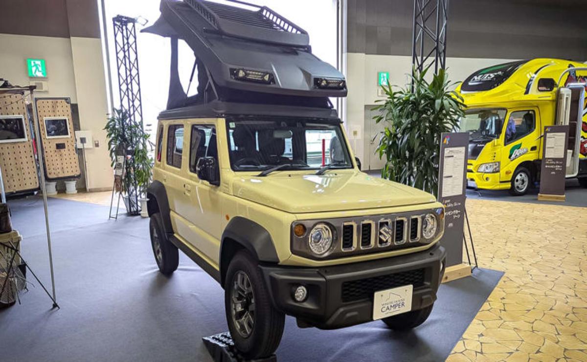 Yellow off-road vehicle with rooftop tent displayed indoors.
