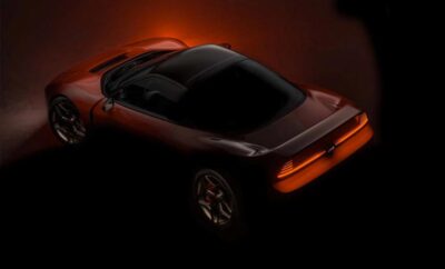 Rear view of a sleek red sports car with glowing taillights in a dark setting.