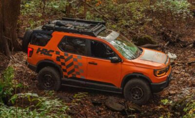 Orange off-road vehicle navigating a forest trail.