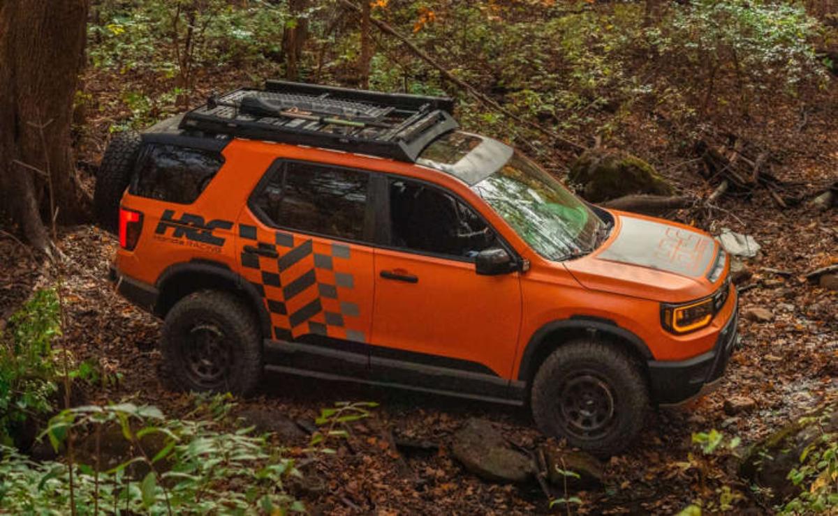 Orange off-road vehicle navigating a forest trail.