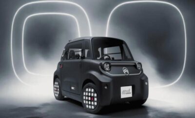 Compact black electric car with futuristic illuminated wheels in a sleek, modern setting.