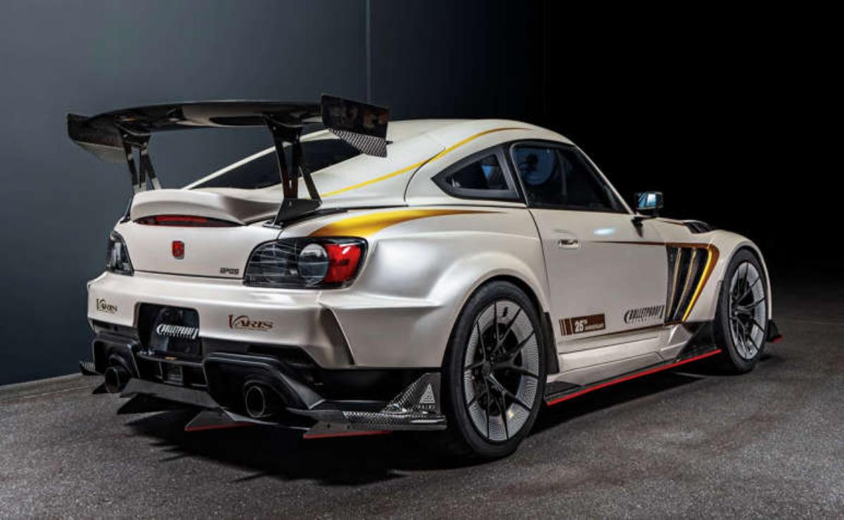 White sports car with aftermarket modifications in a studio setting.