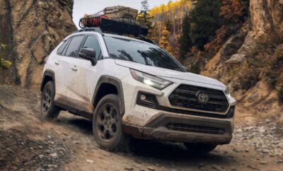 A rugged white SUV with rooftop gear parked on a dirt trail.