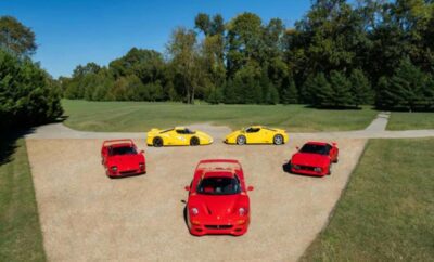 A group of red and yellow sports cars parked on a dirt road near trees.