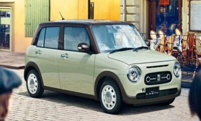 A compact light green car parked on a cobblestone street in an urban area.
