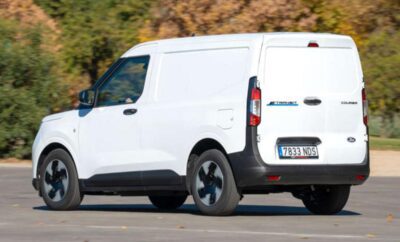 White commercial van parked on a road with autumn trees in the background.