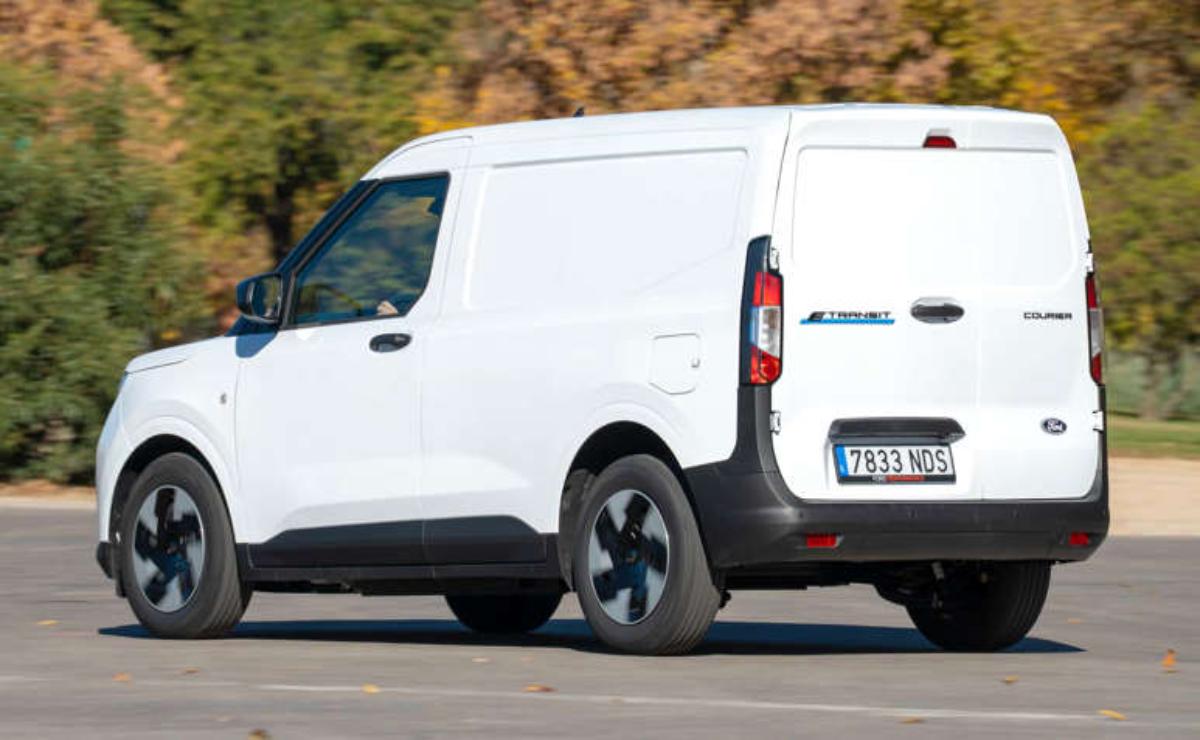 White commercial van parked on a road with autumn trees in the background.