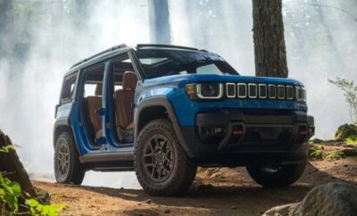 Blue off-road vehicle parked near a tree with doors removed.