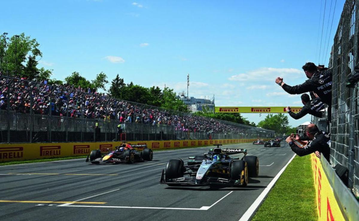 Two Formula 1 cars racing on a track with spectators in the background.