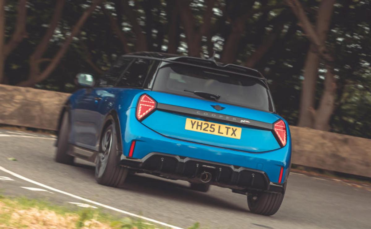 Blue sports car driving on a curved road surrounded by trees.
