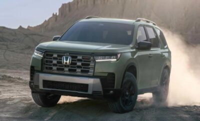 Green Honda SUV parked on a dirt road with mountains in the background.