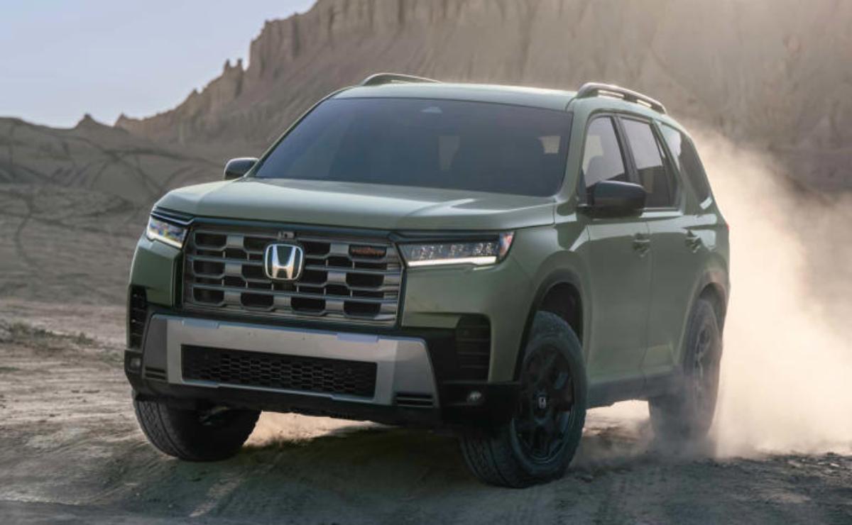 Green Honda SUV parked on a dirt road with mountains in the background.