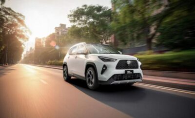 A white Lexus SUV driving on a city street during sunset.