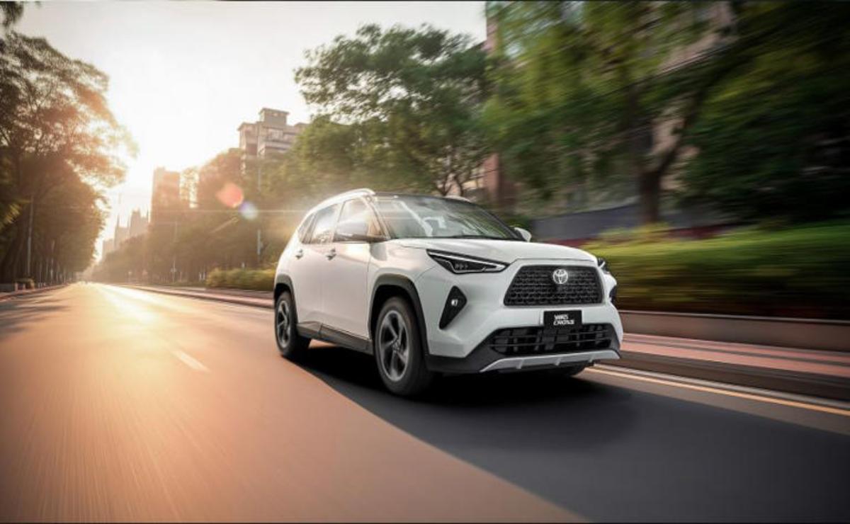 A white Lexus SUV driving on a city street during sunset.