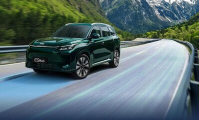 Green SUV driving on a scenic mountain road.
