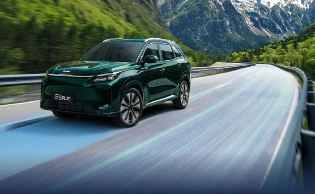 Green SUV driving on a scenic mountain road.